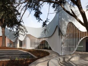 Modern building with flowing white facade and timber slats