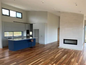 Modern open-plan kitchen with timber floors and fireplace