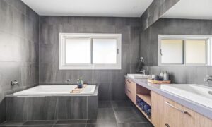 Modern grey tiled bathroom with bath and double vanity