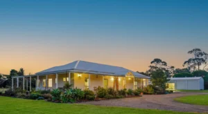 Modern country home with wraparound veranda at dusk