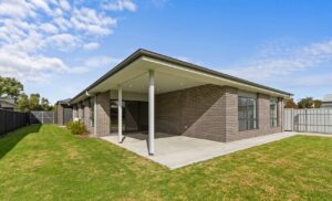 Modern brick home with covered patio and lawn