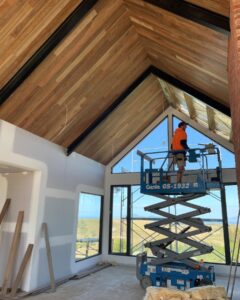 Worker installing timber ceiling on scissor lift