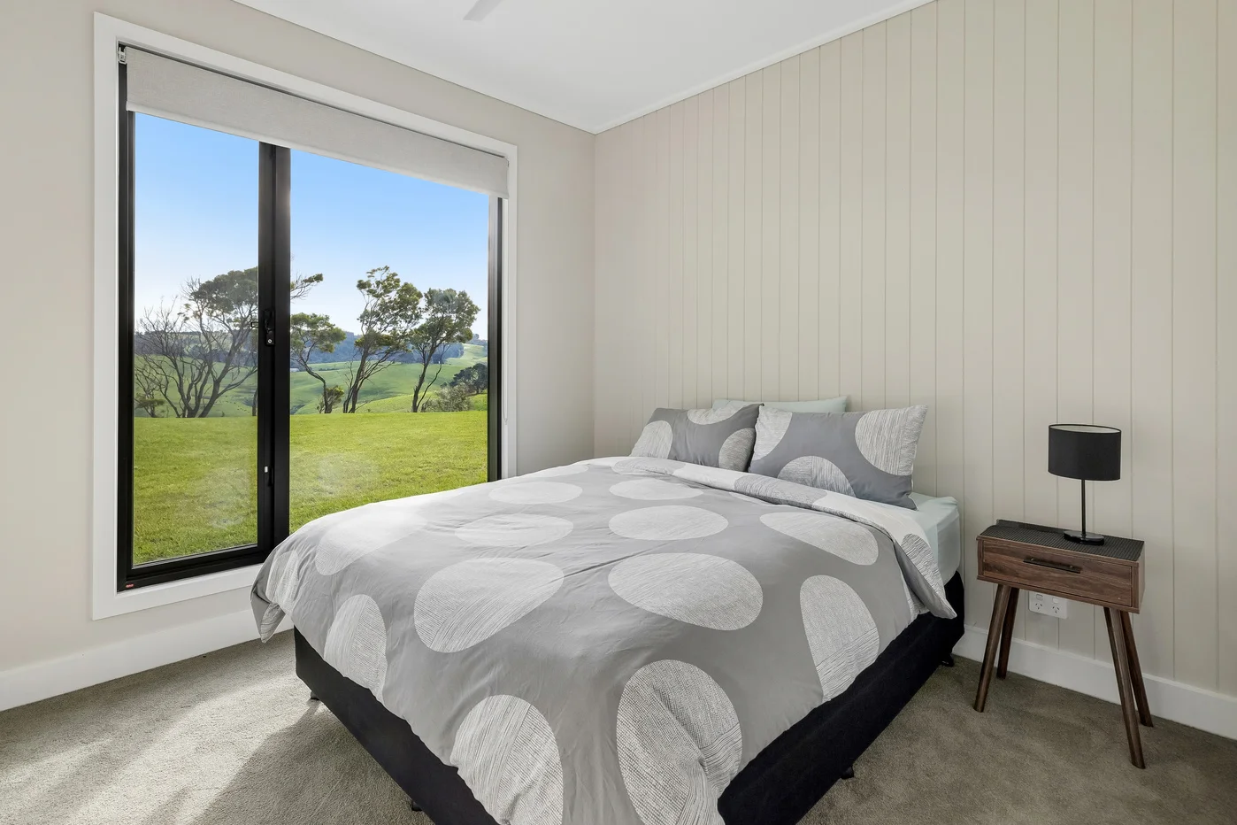 Modern bedroom with large window overlooking green hills