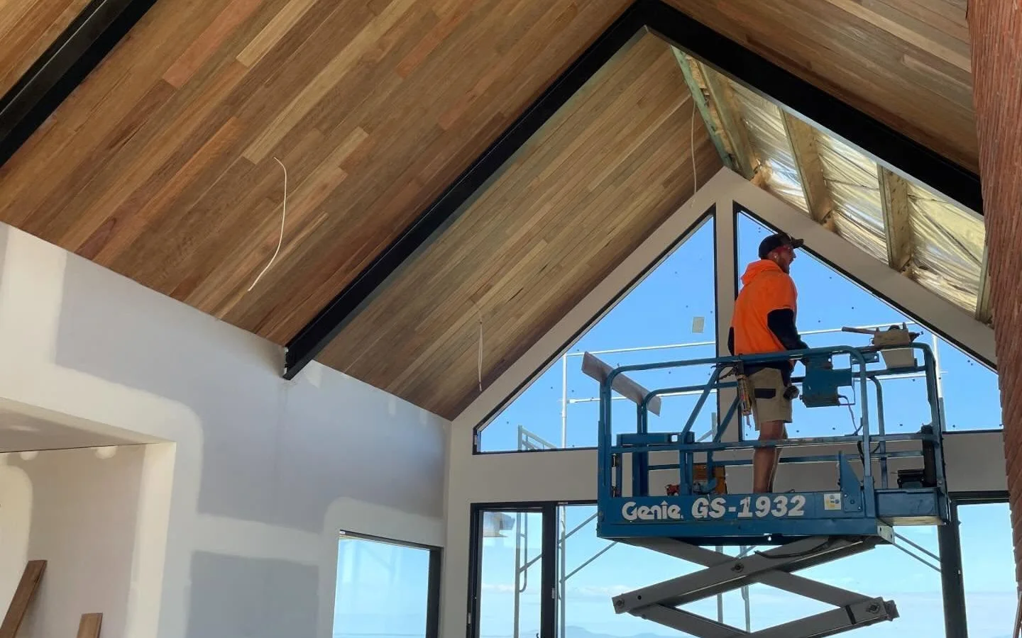 Worker on scissor lift installing timber ceiling